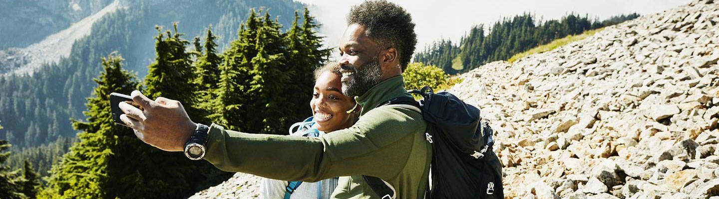 Father and daughter taking selfie while hiking